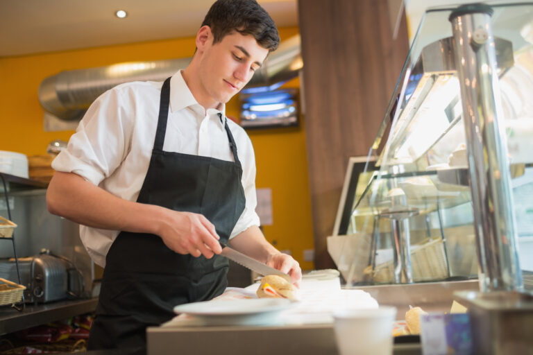 Man working in a busy restaurant kitchen preparing food during service using restaurant phone system