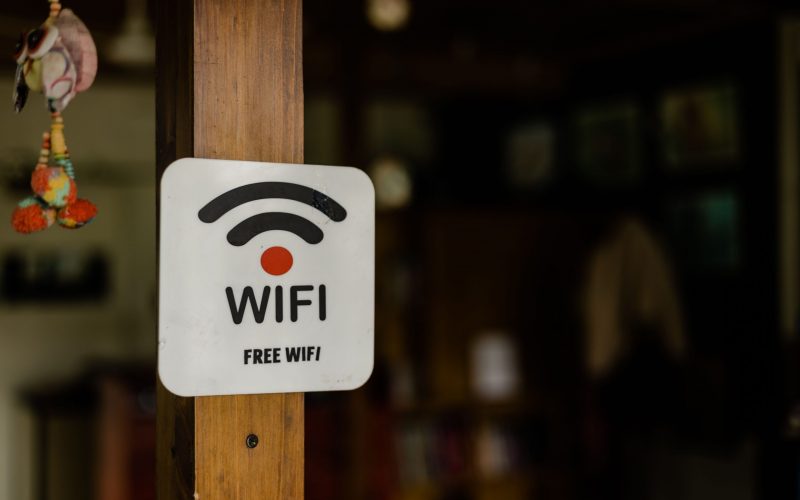 A closeup of a free wifi sign hanging from a wooden plank indoors