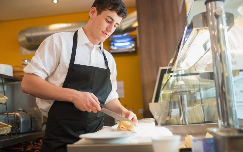 Man working in a busy restaurant kitchen preparing food during service using restaurant phone system