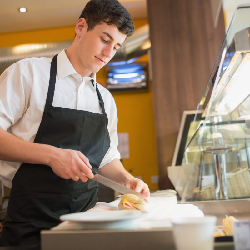 Man working in a busy restaurant kitchen preparing food during service using restaurant phone system